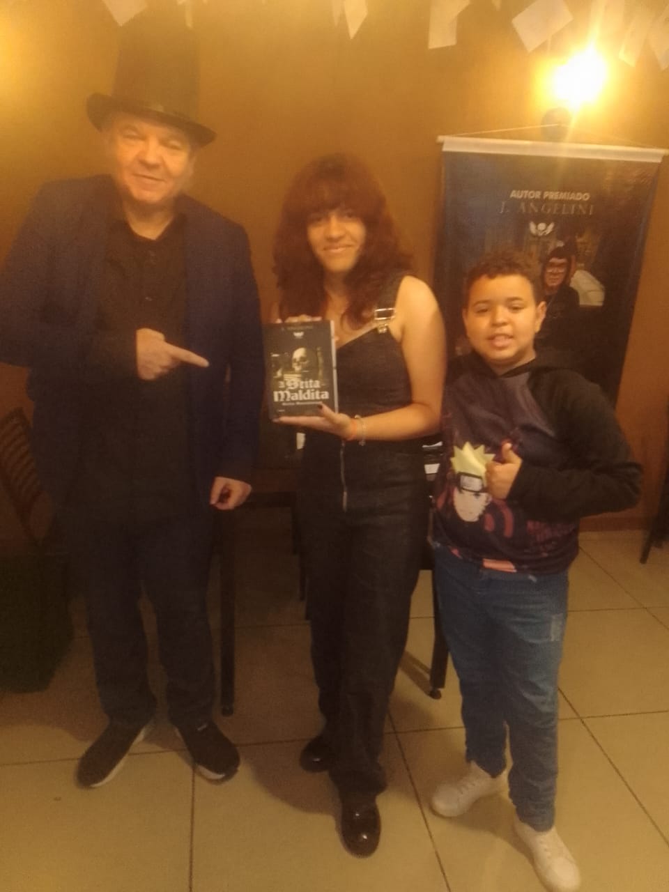 J. Angelini de cartola com leitora e menino no lançamento de A Seita Maldita