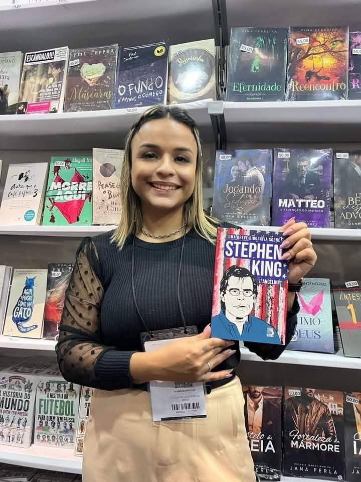 leitora segurando Uma breve biografia sobre Stephen King em livraria, com estante de livros ao fundo
