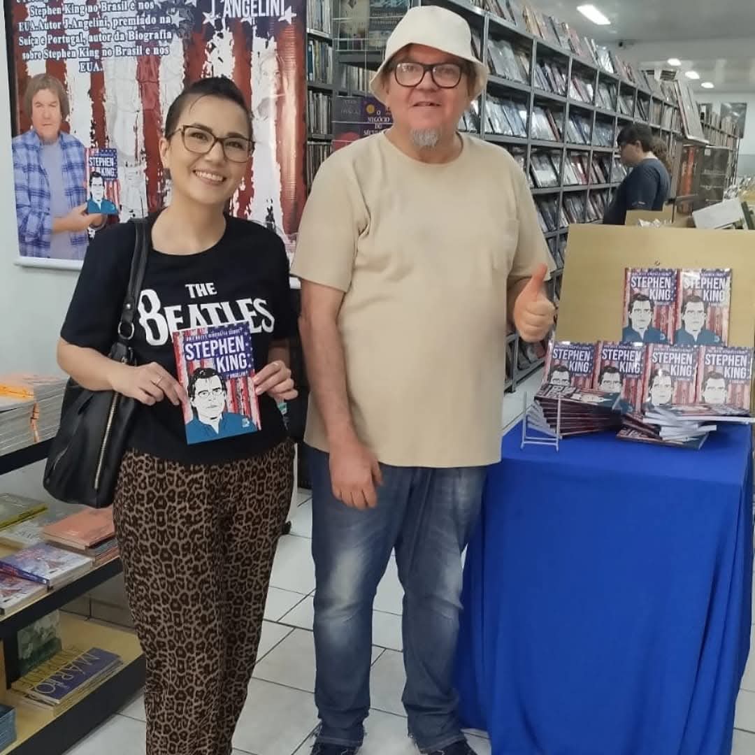 autor em evento de lançamento em livraria, ao lado de fã e display com exemplares